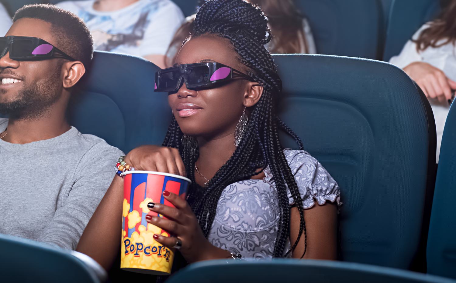 Two people in 3D glasses sharing popcorn at the cinema