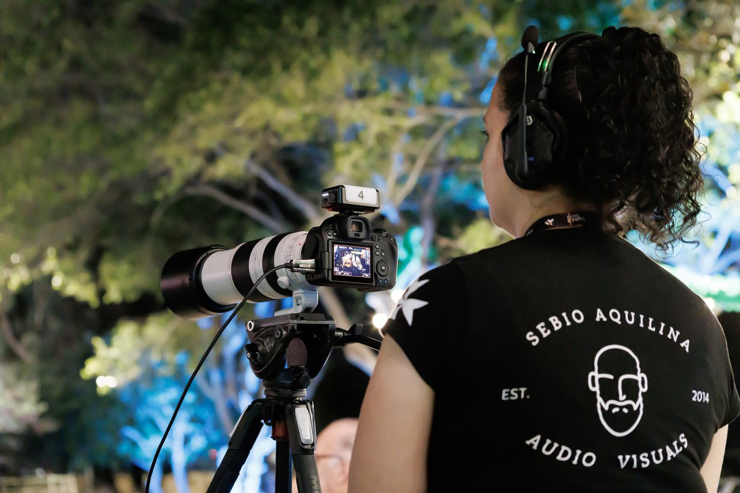 An audio-visual crew member with a camera and a boom microphone