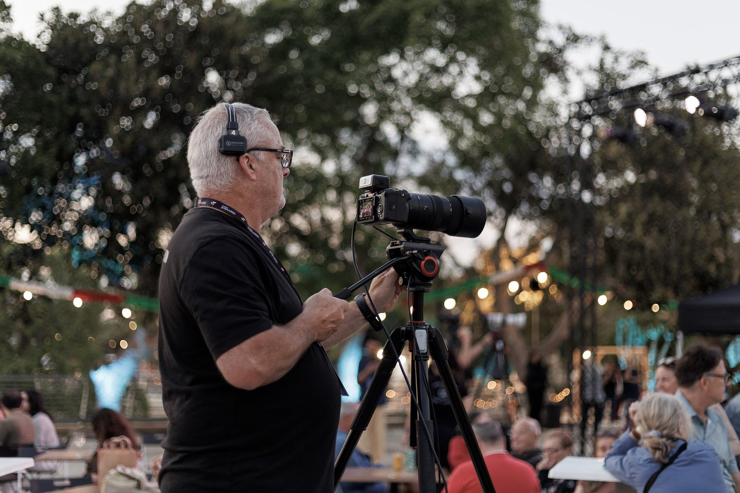A camera operator filming at an outdoor event